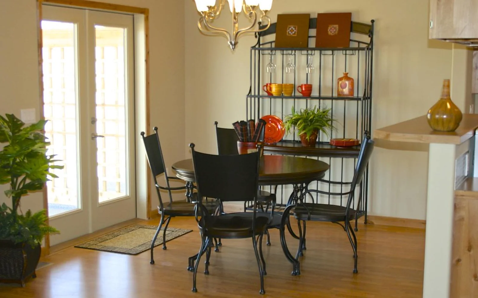 Comedor doméstico luminoso con mesa, plantas y objetos ordenados.