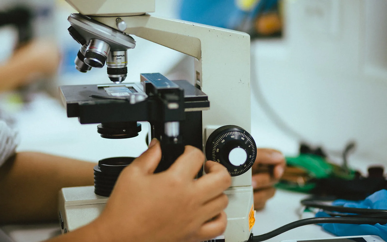 Una investigadora ajusta una muestra bajo el objetivo de un microscopio.