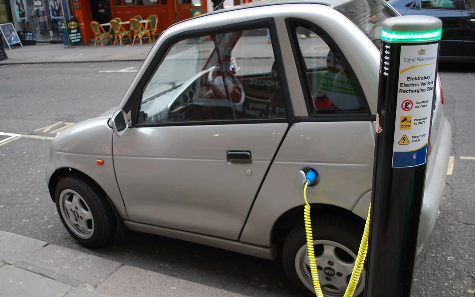 Automóvil eléctrico compacto conectado a un punto de recarga.