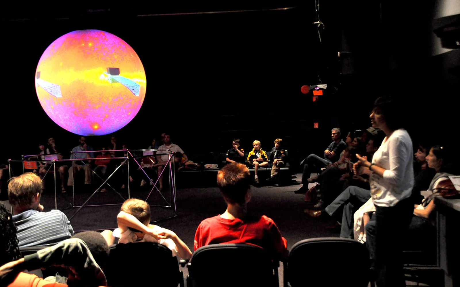 Estudiantes participan en una actividad científica alrededor de una gran esfera iluminada.