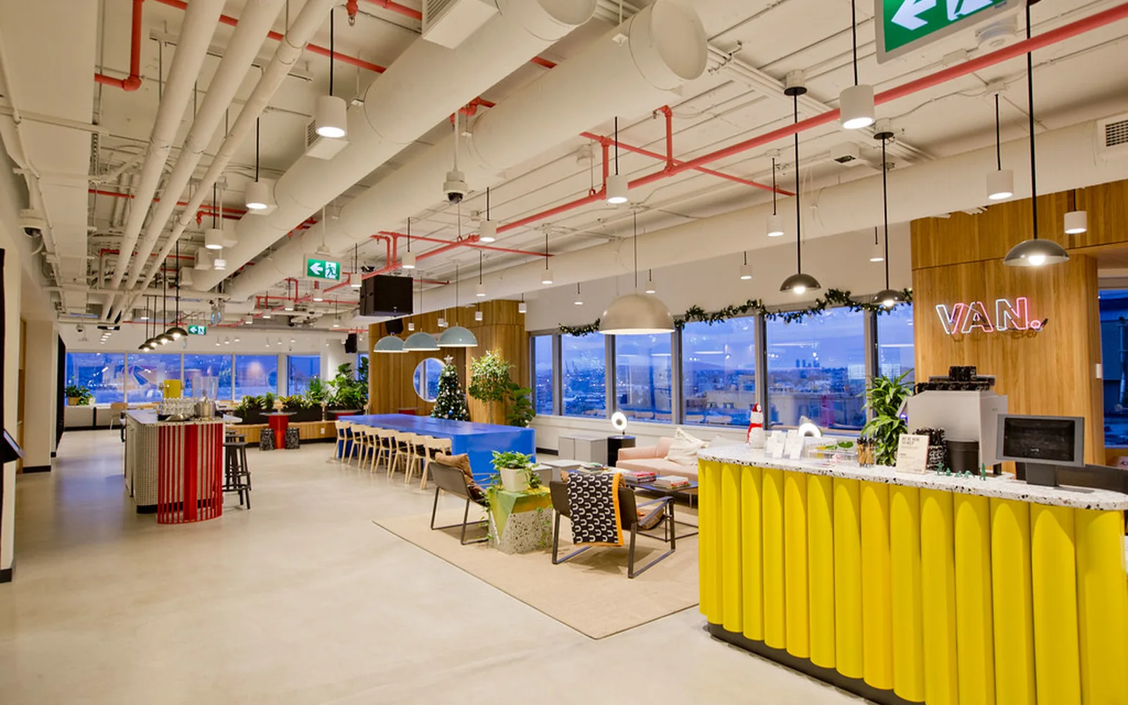 Espacio de trabajo compartido con mesas, pantallas y zonas de reunión.