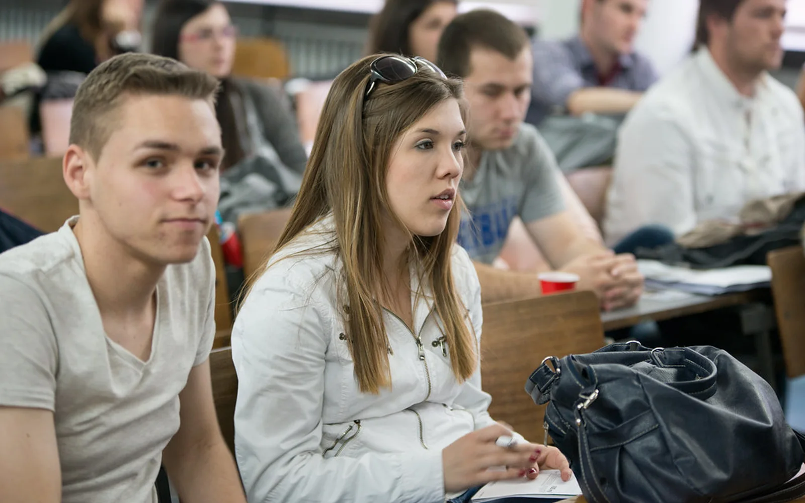 Varias personas jóvenes escuchan una intervención durante un debate público.
