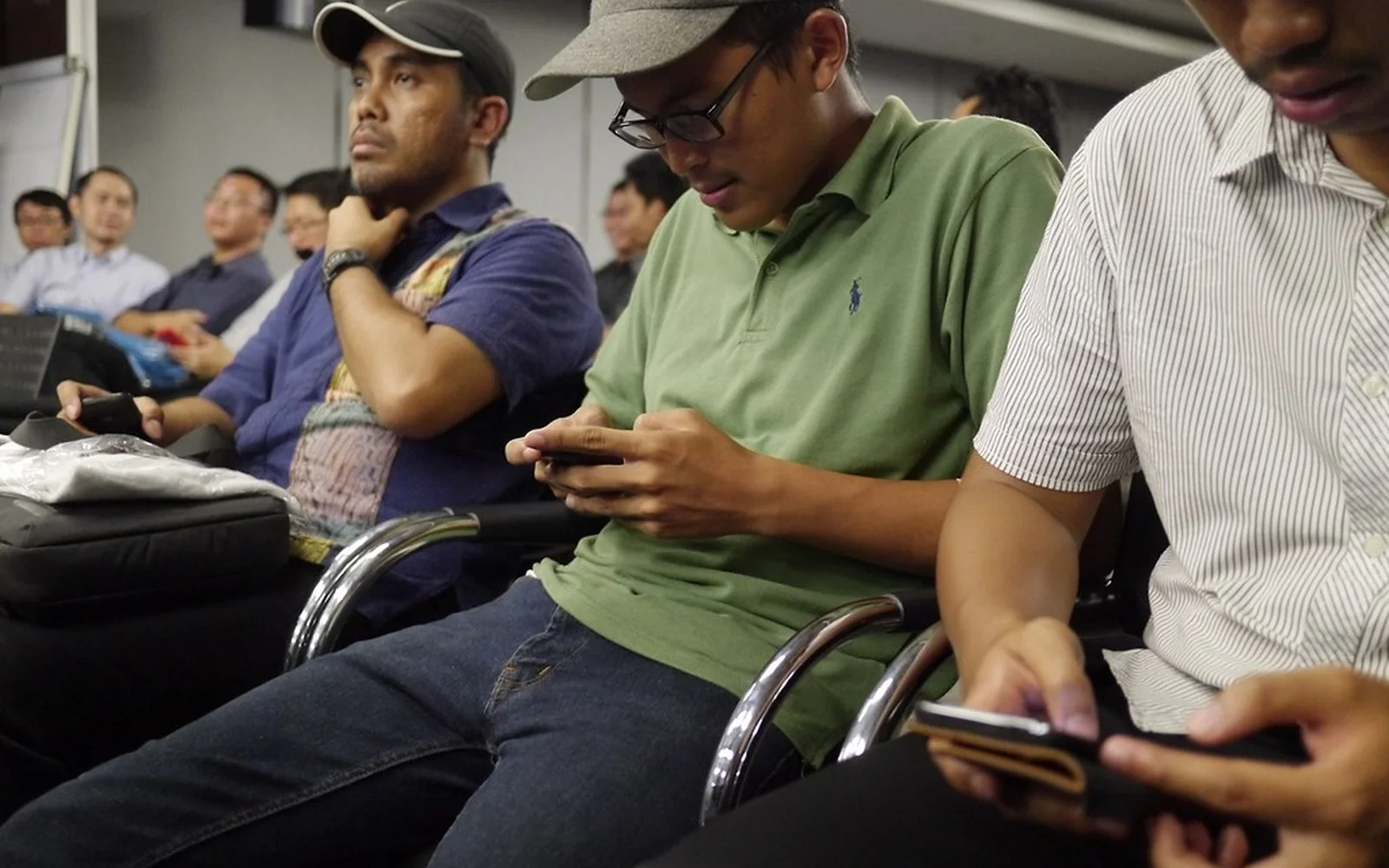 Varias personas miran sus teléfonos durante una charla.