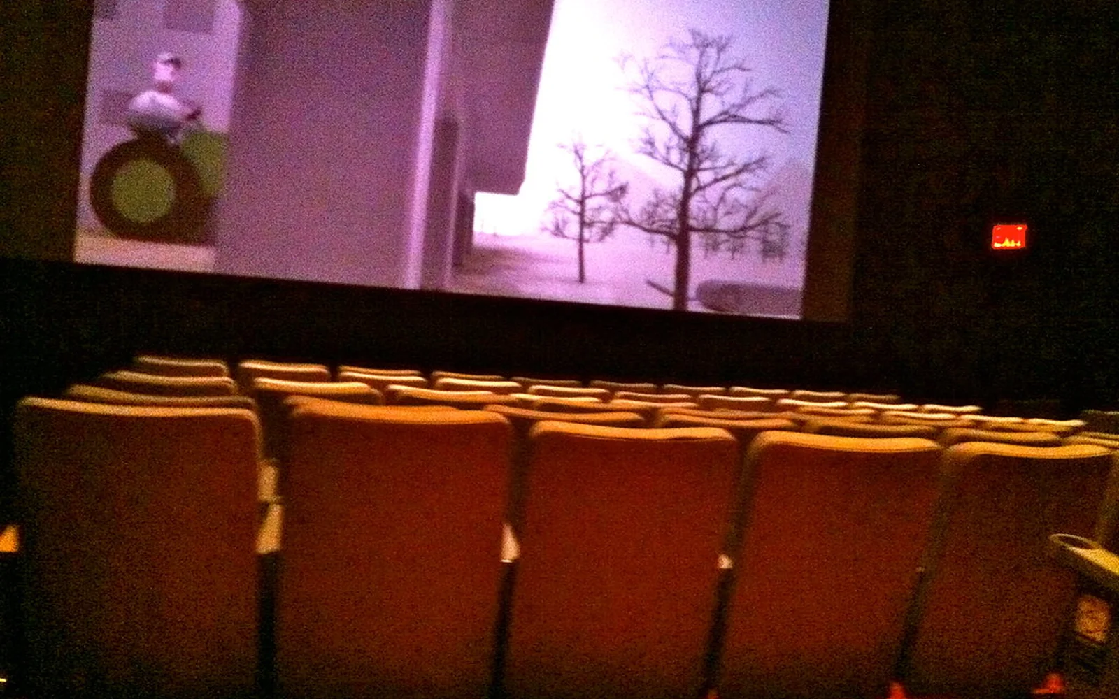 Sala de cine vacía con una proyección en la pantalla.