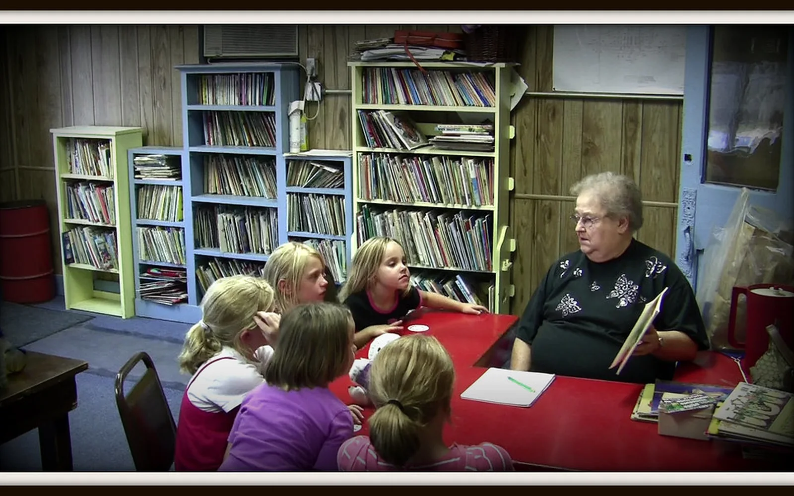 Un grupo de niñas y adultas comparte una actividad de lectura en una biblioteca comunitaria.
