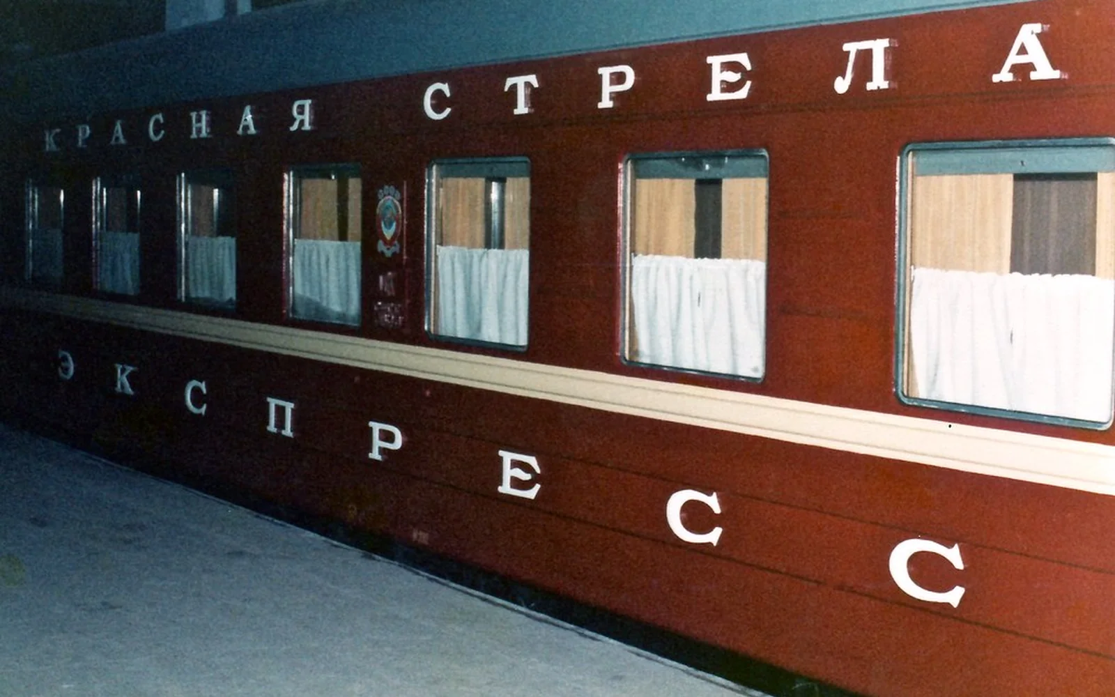 Vagón de un tren nocturno rojo detenido junto a un andén.